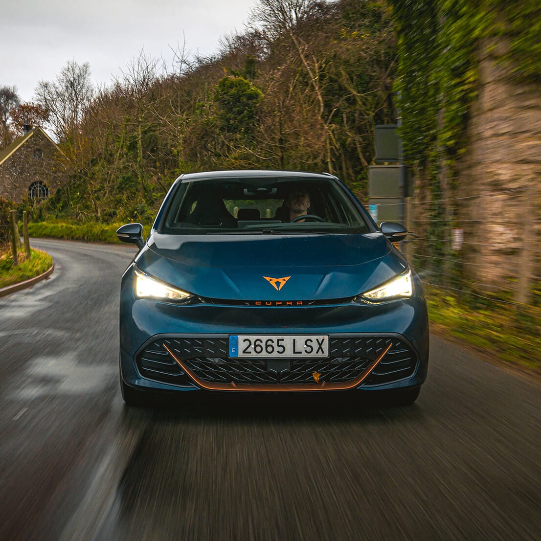 A CUPRA Born driving toward the camera on a country road