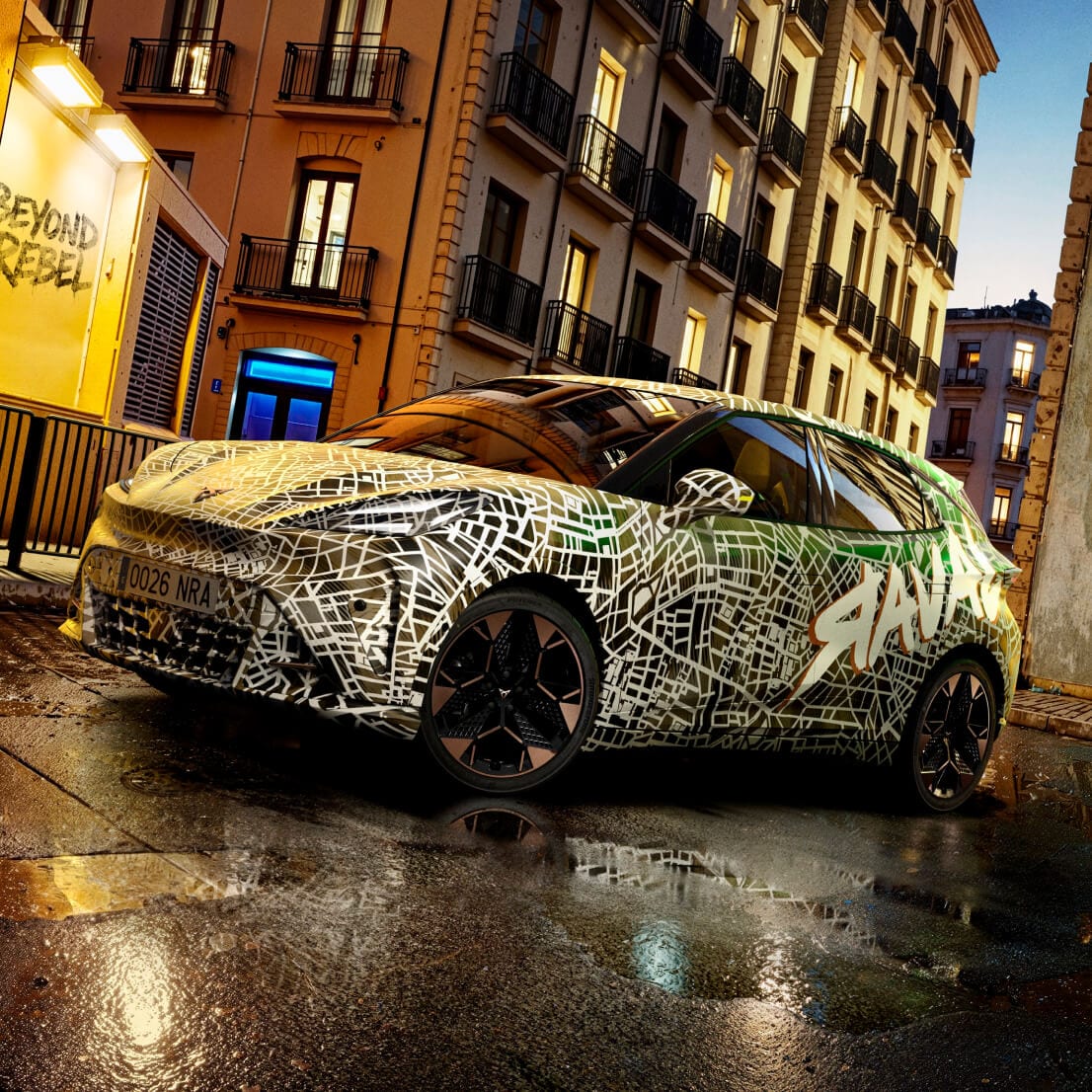 The CUPRA Raval in camouflage exterior wrapping against an urban background at dusk