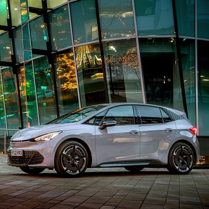 Side shot of a white CUPRA Born against an office building