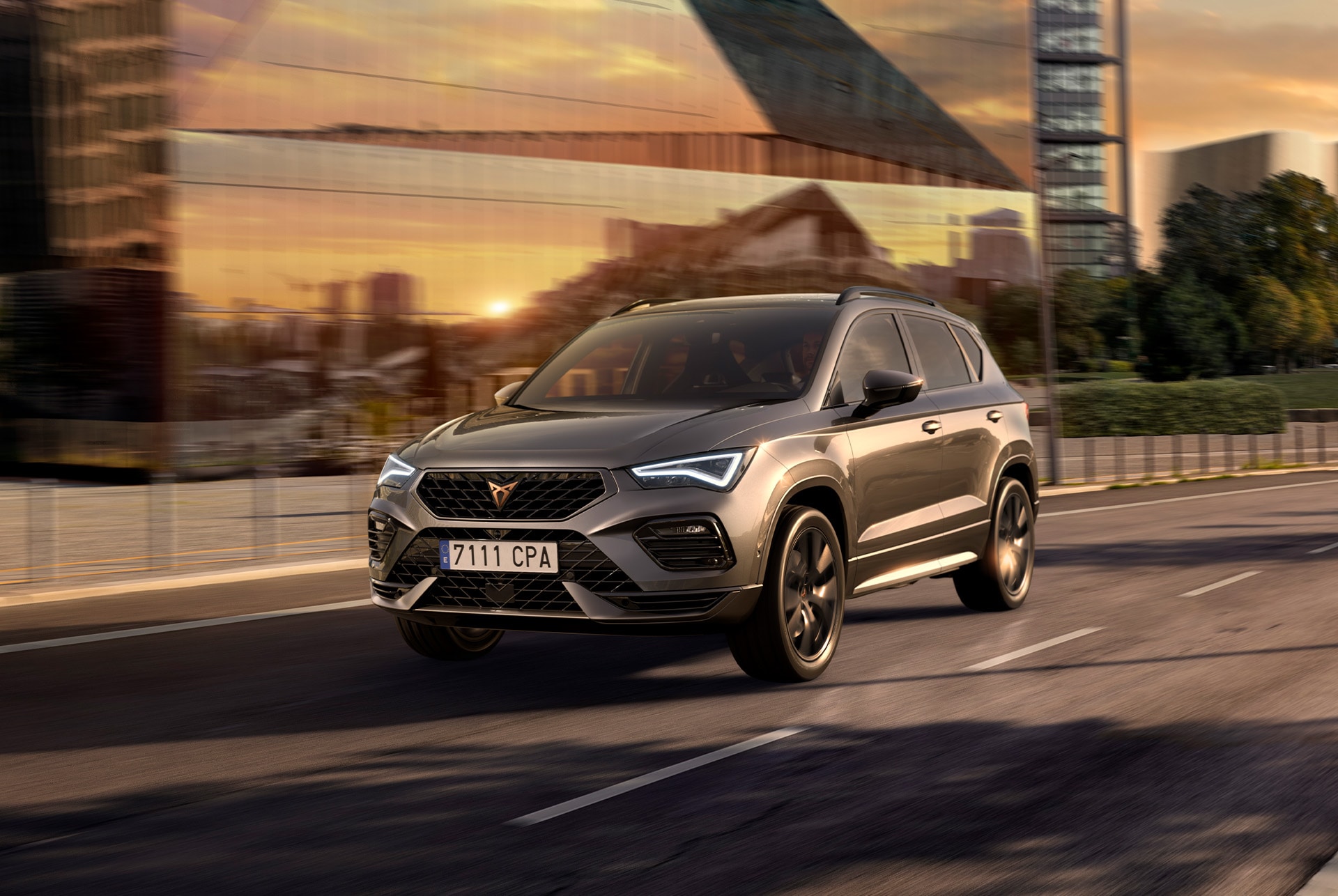 CUPRA Ateca SUV driving on a city road at sunset. The SUV is available with engines in 150hp and 190hp with 4-wheel drive, offering less emissions and fuel consumption.