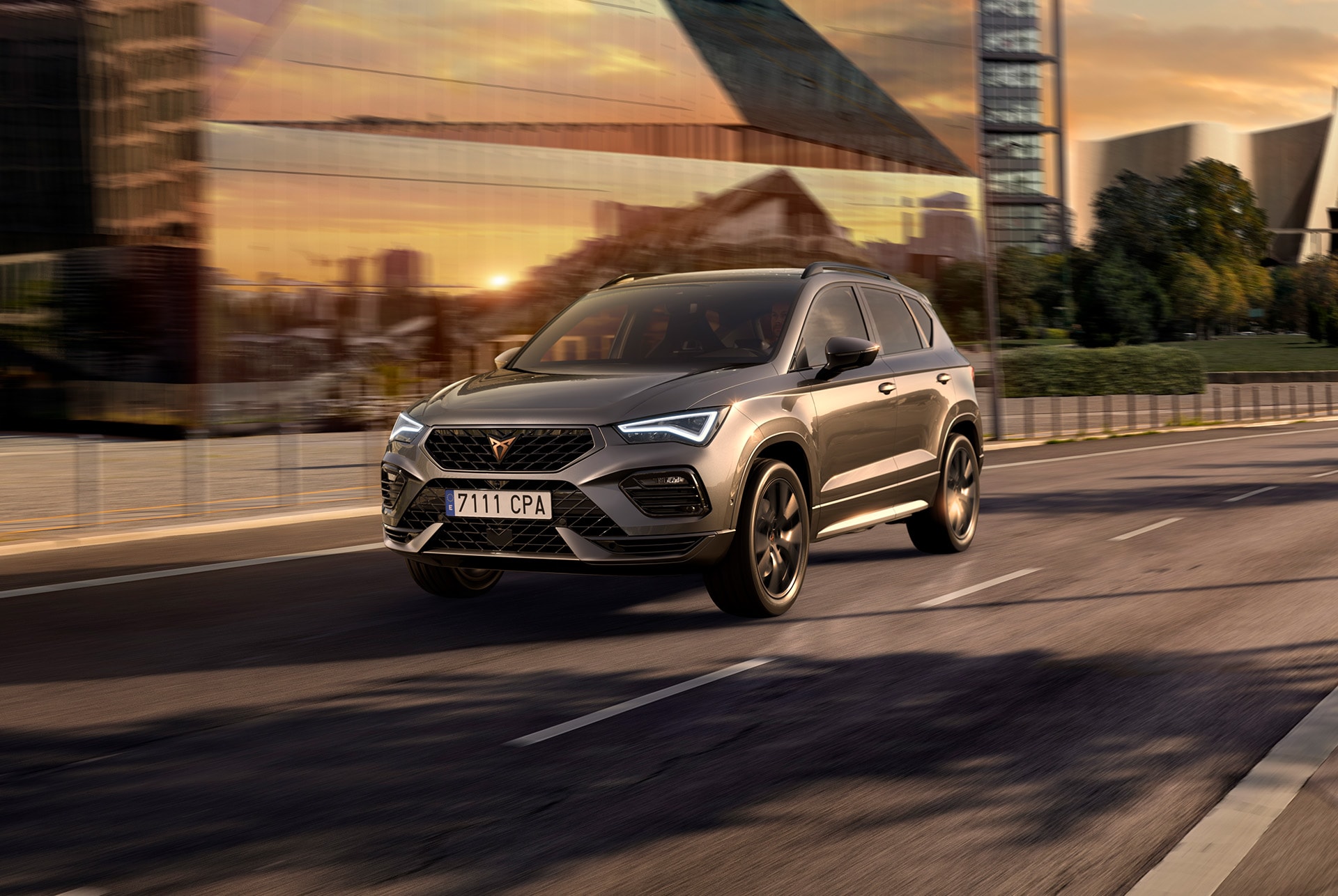 A grey cupra ateca suv displayed against a white background. The car features a bold front grille, led headlights and copper accent alloy wheels, highlighting its sporty car design.
