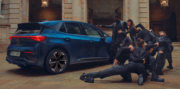 people dancing beside an Aurora Blue CUPRA Born