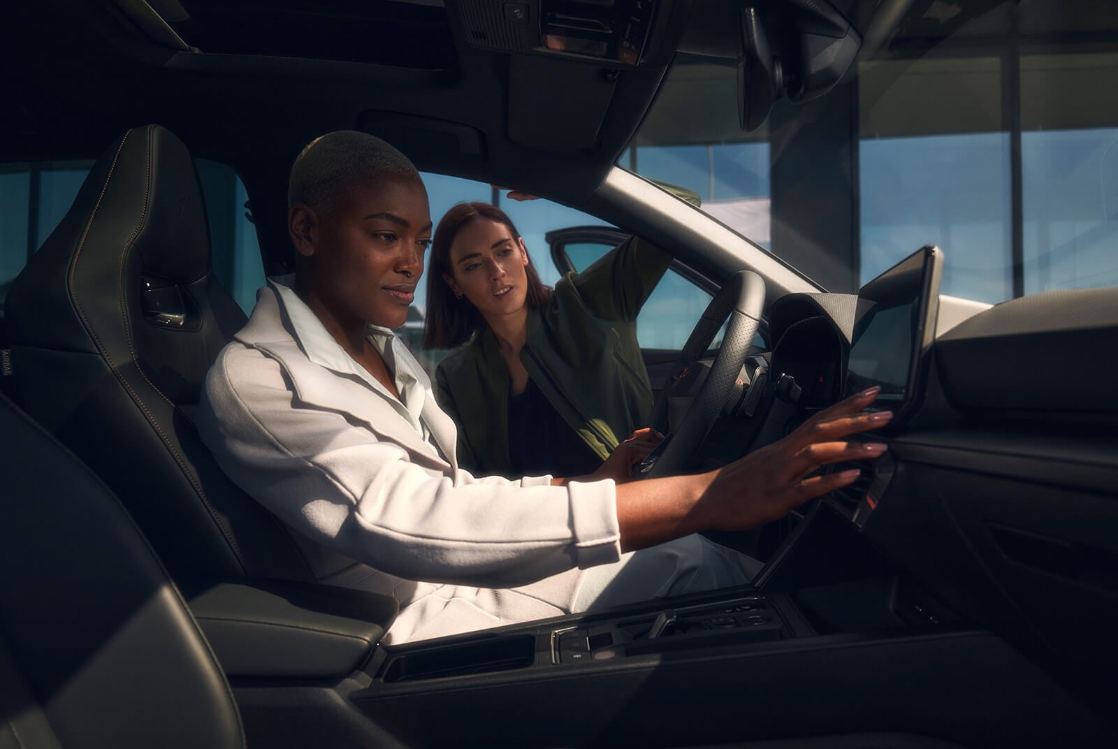 Two individuals inside a CUPRA car, one of them is using the digital dashboard so represent the idea that you can set up your car to suit your preferences.