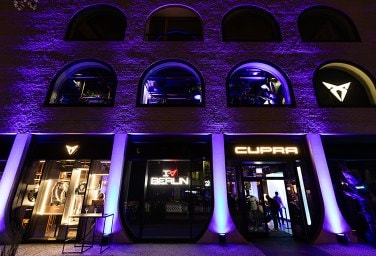 purple lights shining on a building that looks like an old warehouse with CUPRA logos on it 