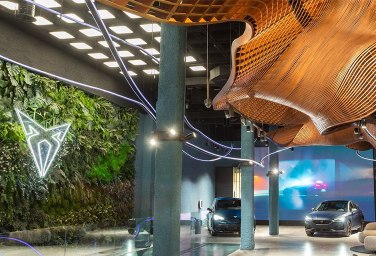 a white neon logo against foliage in CUPRA city garage Madrid