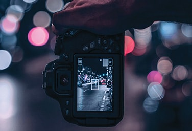 A person holding a camera that is focusing on an object in the middle of a road at night