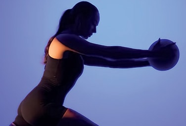 A woman holding a ball in a room with a purple background