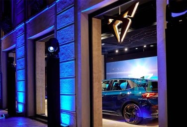 CUPRA city garage in Milan with blue lights shining on cars in the showroom window