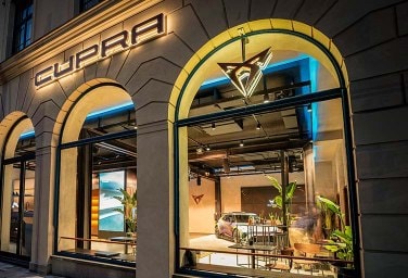 CUPRA city garage in Munich with cars on display in the showroom and the CUPRA logo above the door