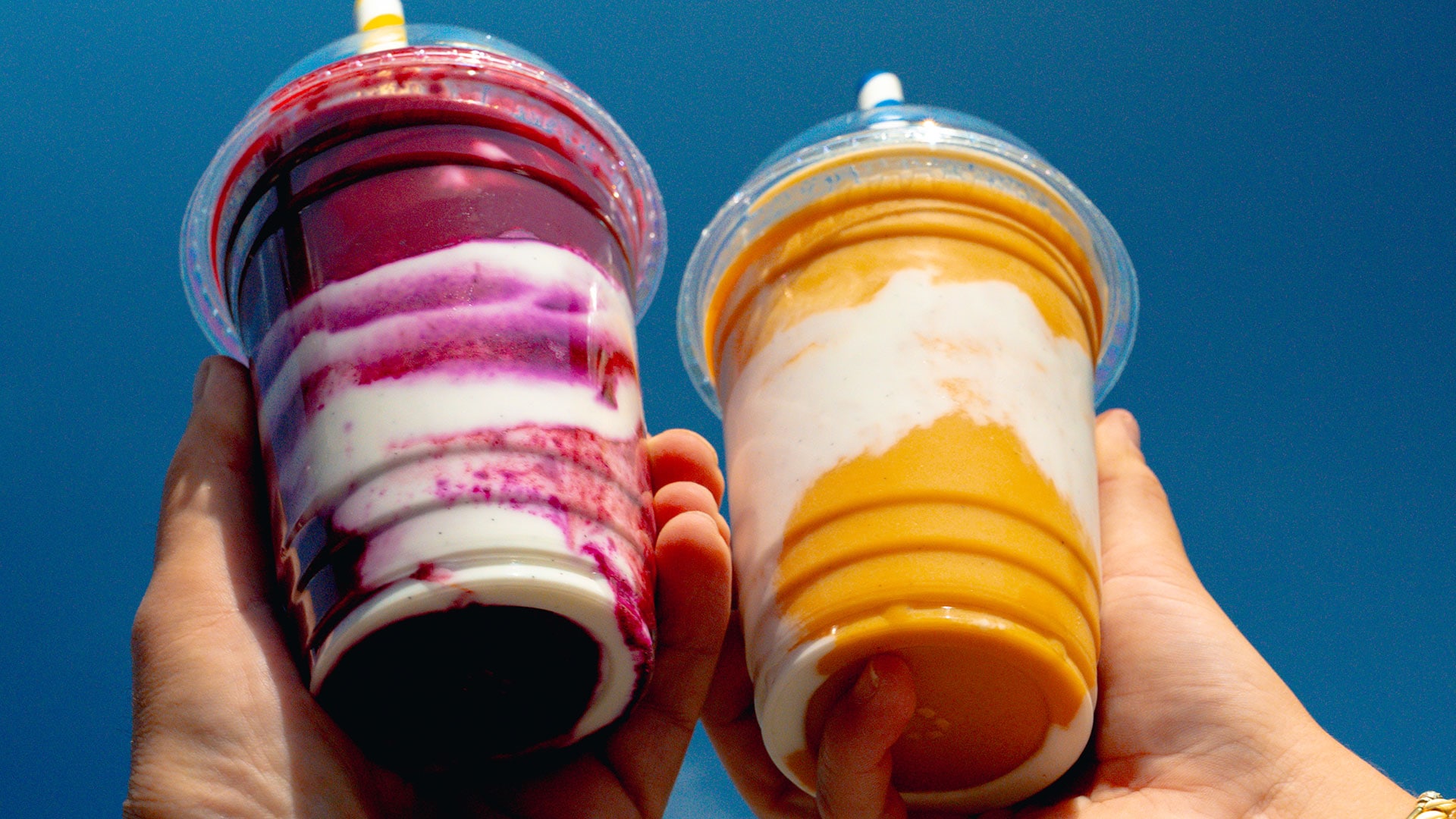 Two hands holding two smoothies
