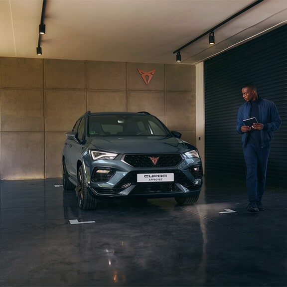 A man walking next to a CUPRA Formentor and holding a clipboard