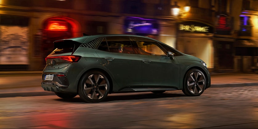 A CUPRA Born driving through a city street at night