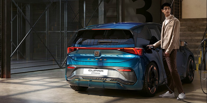 A man standing next to a CUPRA Born at a charging station