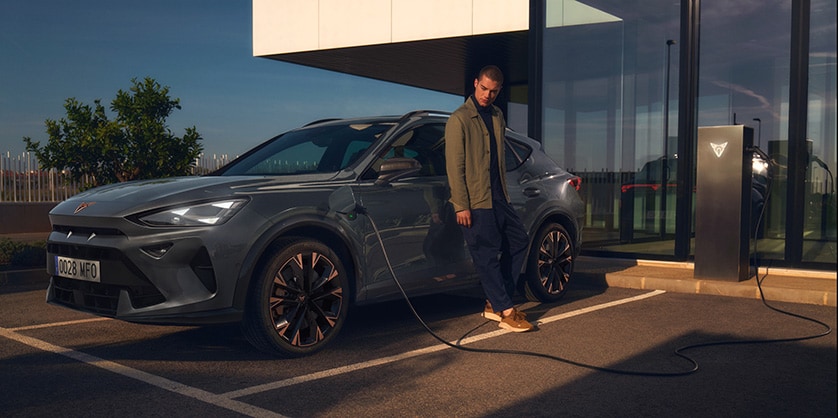 A man leaning on a CUPRA Formentor while it is charging