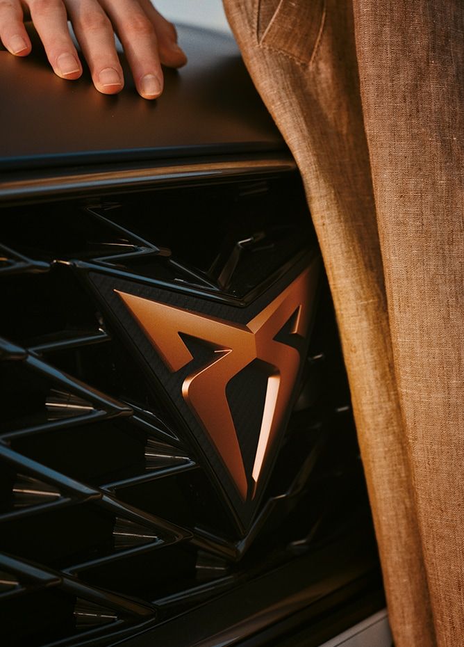 Lady standing by a CUPRA car with the front grill and CUPRA badge visible