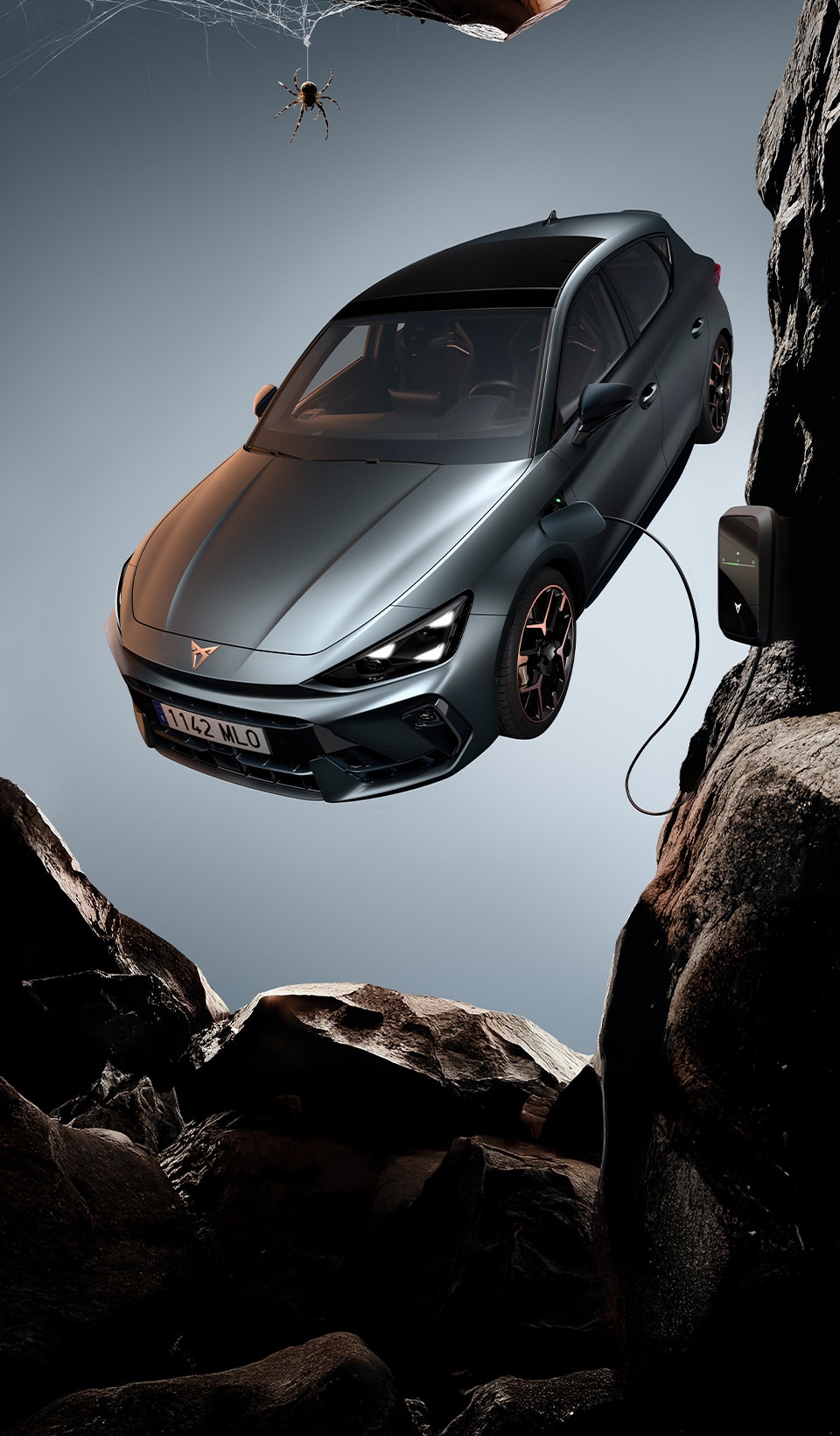 A CUPRA Leon hatchback seen from an elevated angle with its headlights on, next to a person covered in dark, flowing fabric that drapes onto the ground