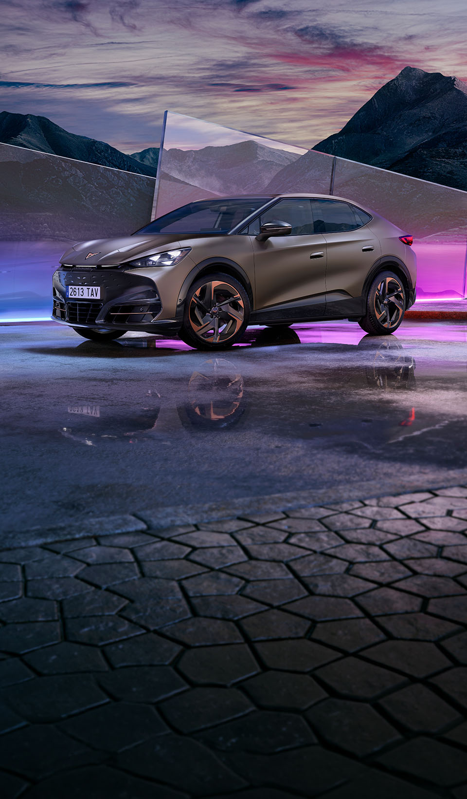 Three-quarter front view of a century bronze matt CUPRA Tavascan, set against geometric glass panels reflecting a mountain landscape and purple neon lights.