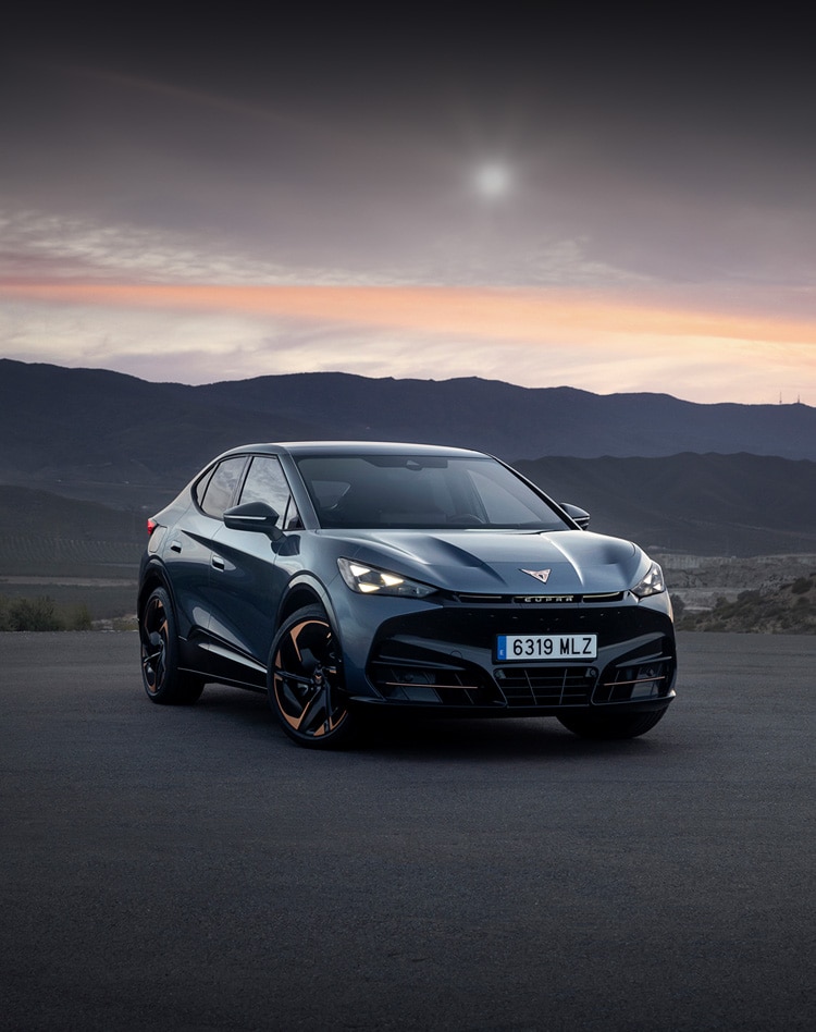 A CUPRA Tavascan parked amongst a rugged hilly background