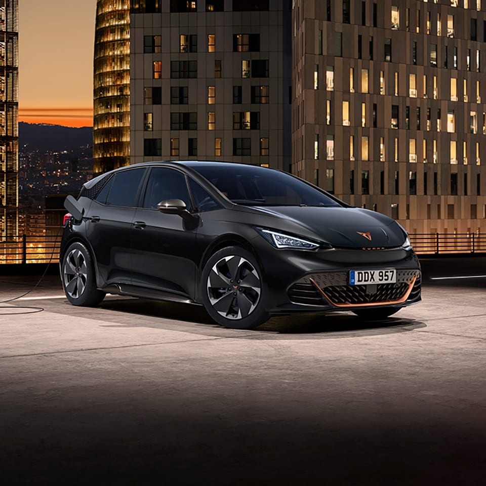 A CUPRA Born in a rooftop car park with city buildings in the background