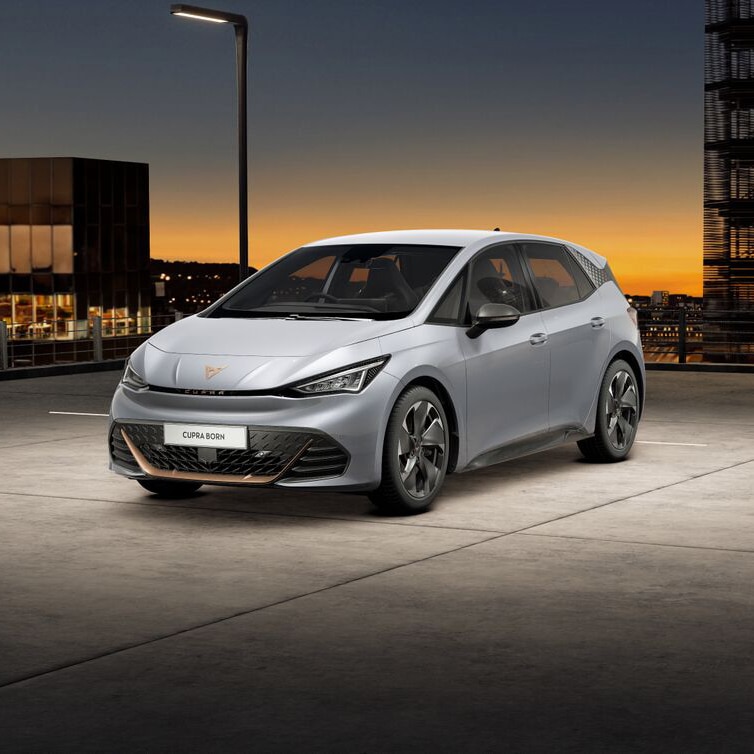 A CUPRA Born in a rooftop car park with city buildings in the background