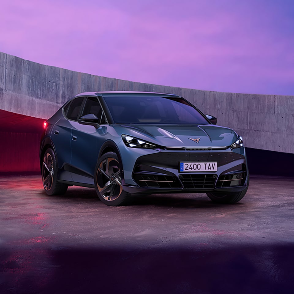 A CUPRA Tavascan front facing in a car park with purple lighting