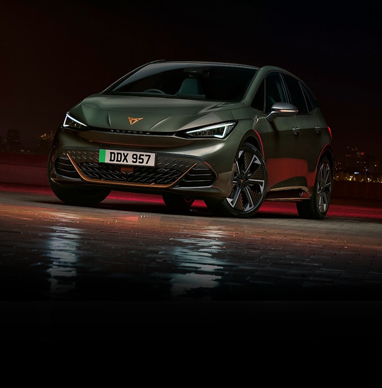 A CUPRA Born at night with a city skyline in the background