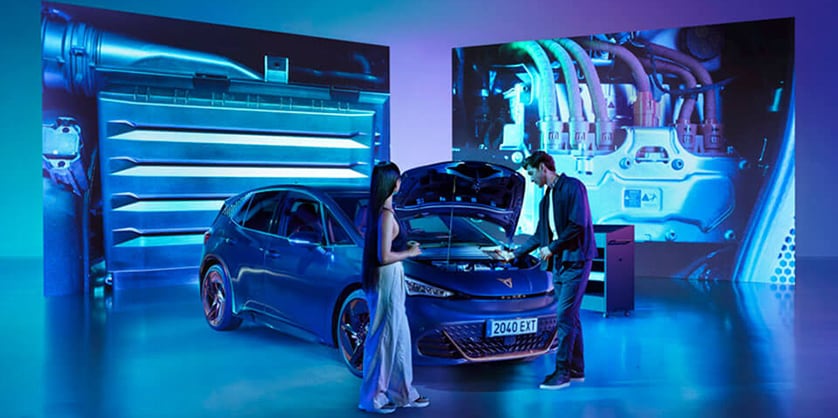 A CUPRA Born in a garage being inspected by a mechanic and a customer closeby