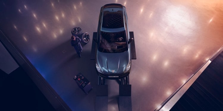 A CUPRA Tavascan at a CUPRA service centre on a ramp with a service representative holding a tablet