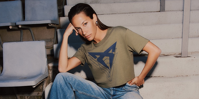 A woman in jeans and a T-shirt sitting on some steps, looking at the camera
