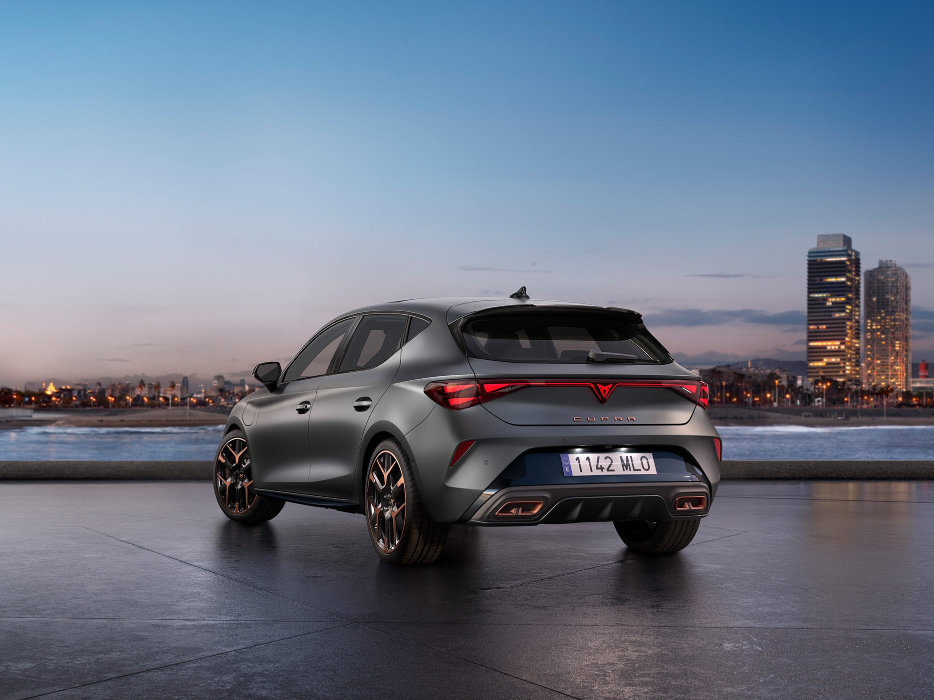 The new CUPRA Leon parked in an urban area, facing the city buildings at sunset.