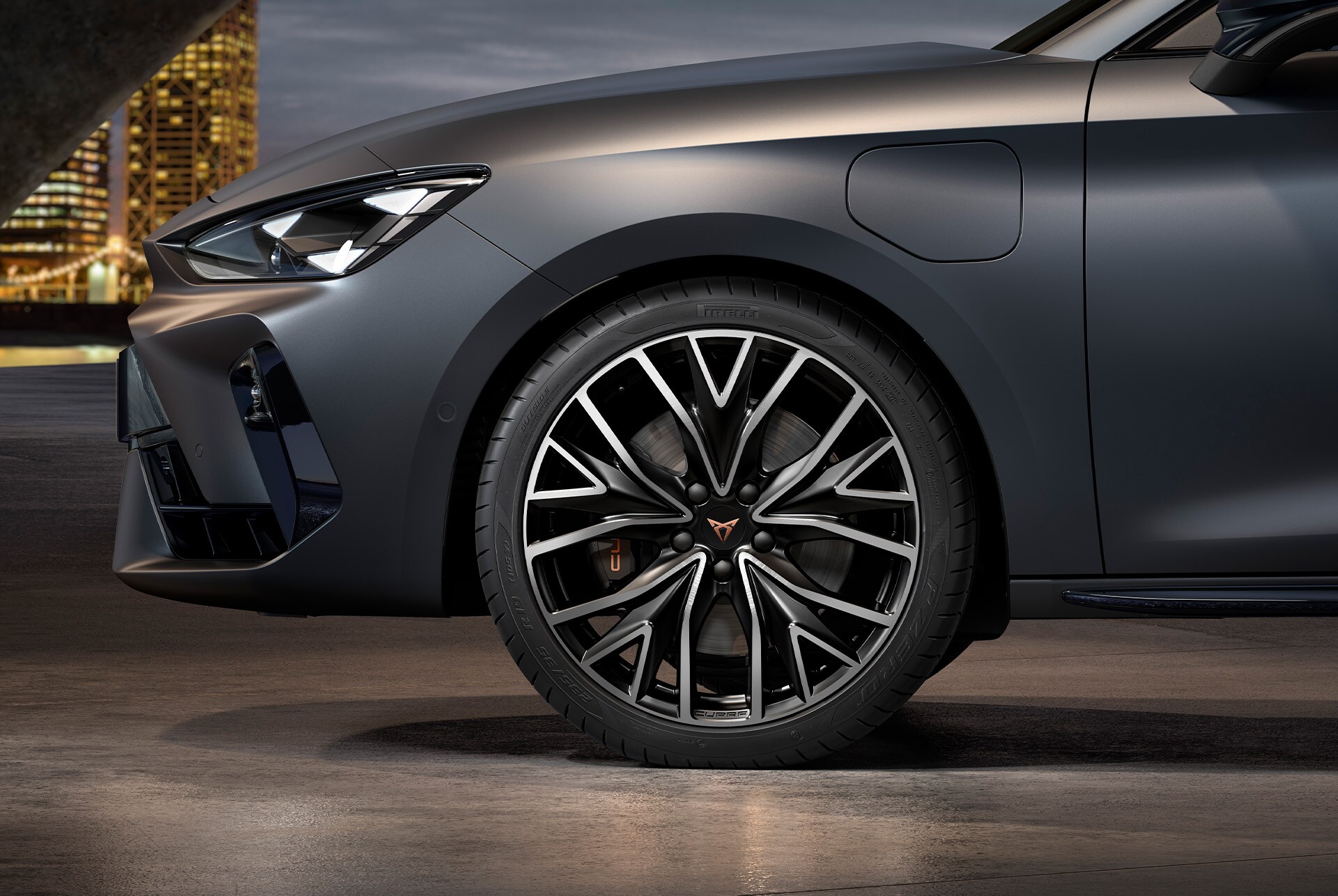 front side view of left mistral machined alloy wheels in silver and black for the CUPRA Leon Estate, tyres, signature headlights and grey body