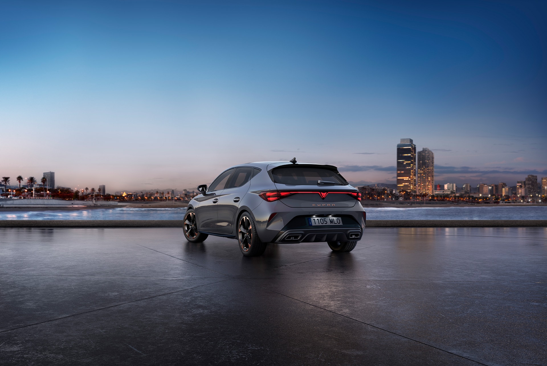 Rear view shot of a CUPRA Leon glossy grey car model with dynamic chassis control, plus black and copper alloy wheels. City in the background at sunset.