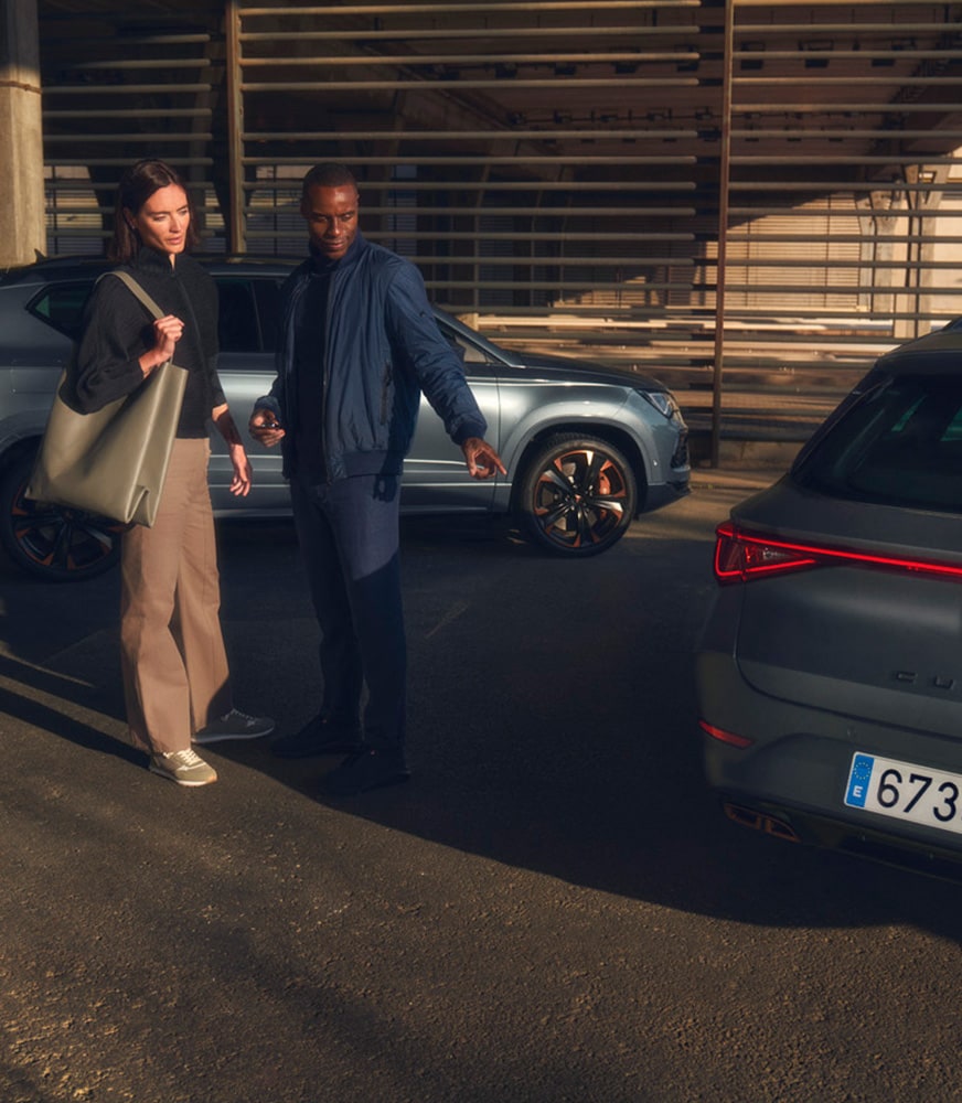 CUPRA Master employee speaking with a customer next to CUPRA car. 