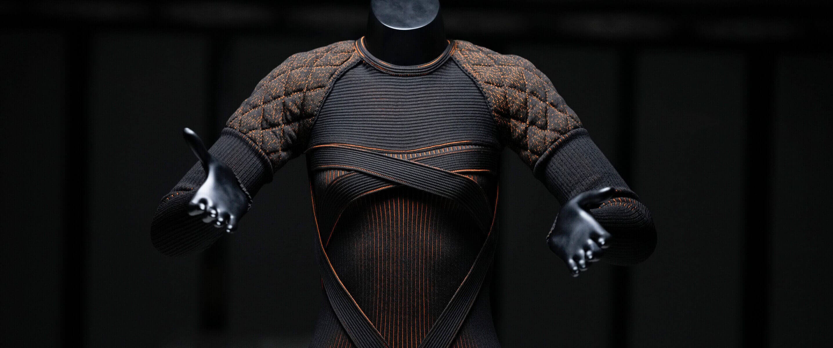 A textured  top displayed on a black mannequin against a dark background, resting on a white surface.