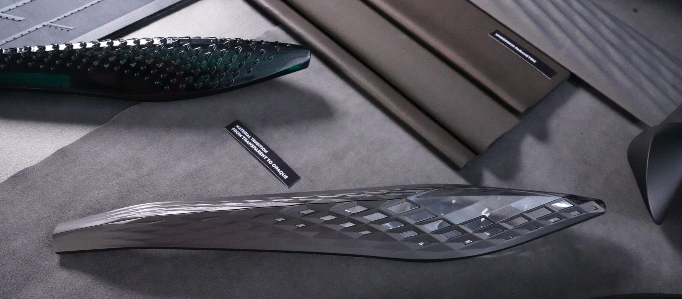 A several gray, dark gray and dark-green automotive design pieces are displayed on a gray surface.
