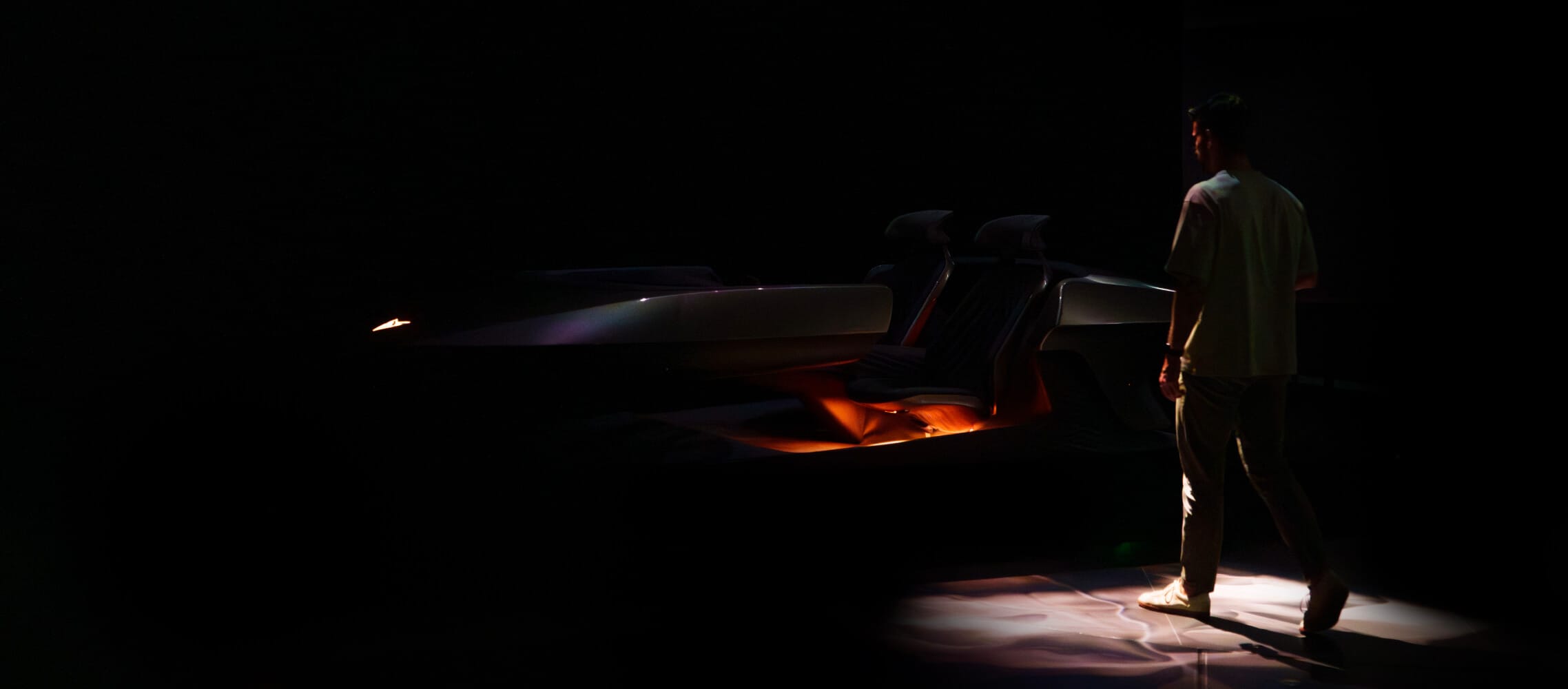 A futuristic car interior view from the back seats showcasing the modern design and lighting elements.