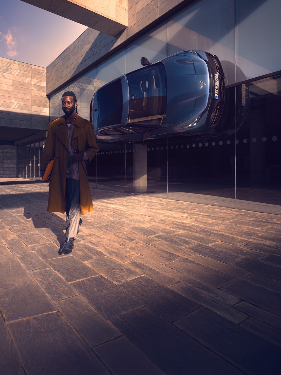 A man walking away from a building with a CUPRA Tavascan hanging on the side of the wall A man walking away from a building with a CUPRA Tavascan hanging on the side of the wall