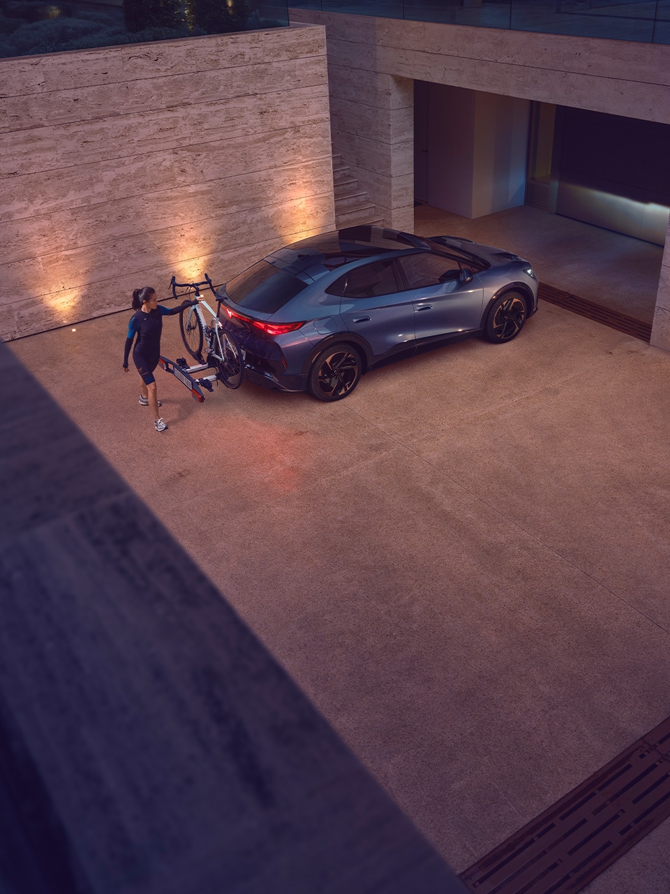 A woman holding onto a bicycle that's mounted to the back of a CUPRA Tavascan A woman holding onto a bicycle that's mounted to the back of a CUPRA Tavascan