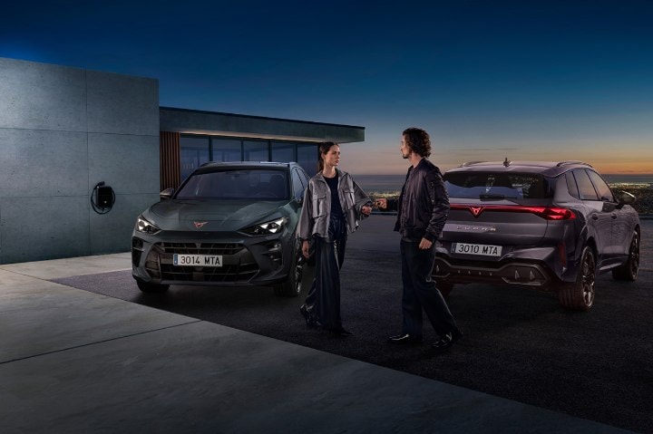A man and a woman exchanging keys behind them are two CUPRA vehicles parked