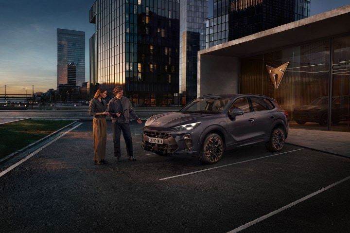 Two people standing whilst admiring a dark navy CUPRA Terramar Two people standing whilst admiring a dark navy CUPRA Terramar