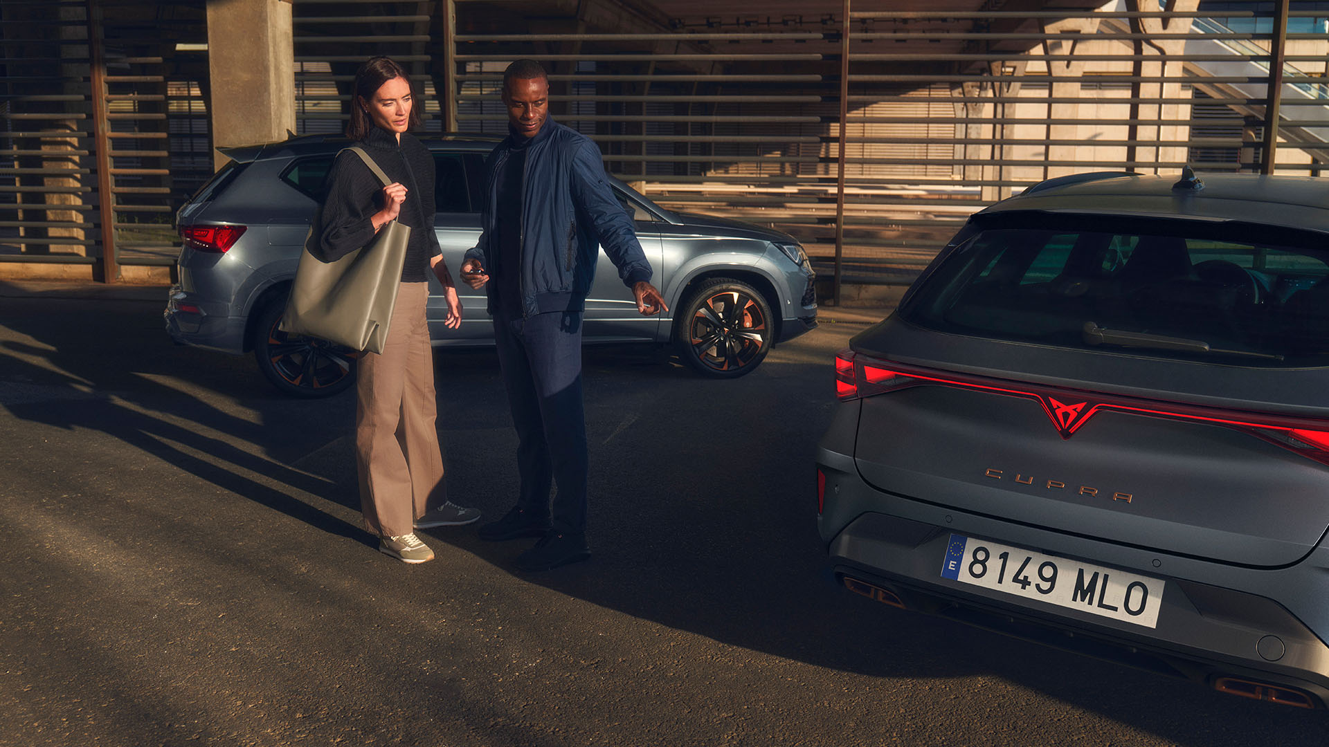 Two people looking closely at the LED rear-view lights of a CUPRA car