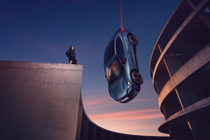 a blue CUPRA Tavascan hanging at concrete setting with sky backdrop a blue CUPRA Tavascan hanging at concrete setting with sky backdrop