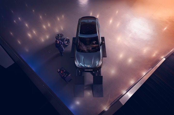 An ariel view of the Tavascan at a CUPRA service centre on a ramp with a service representative next to it An ariel view of the Tavascan at a CUPRA service centre on a ramp with a service representative next to it