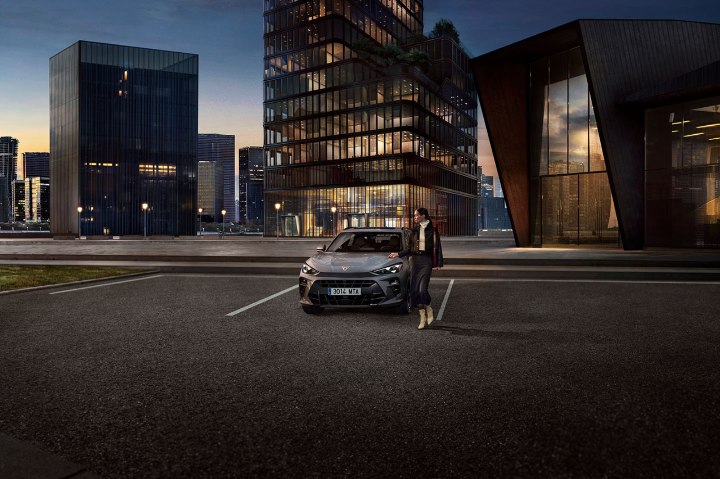 A woman walking away from a silver CUPRA Terramar parked in a city