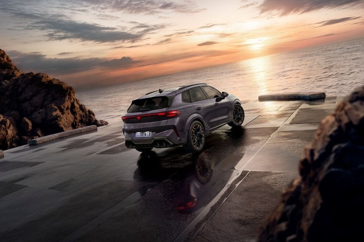 Rear view of a CUPRA Terramar parked in front of the sea with sun setting in the distance