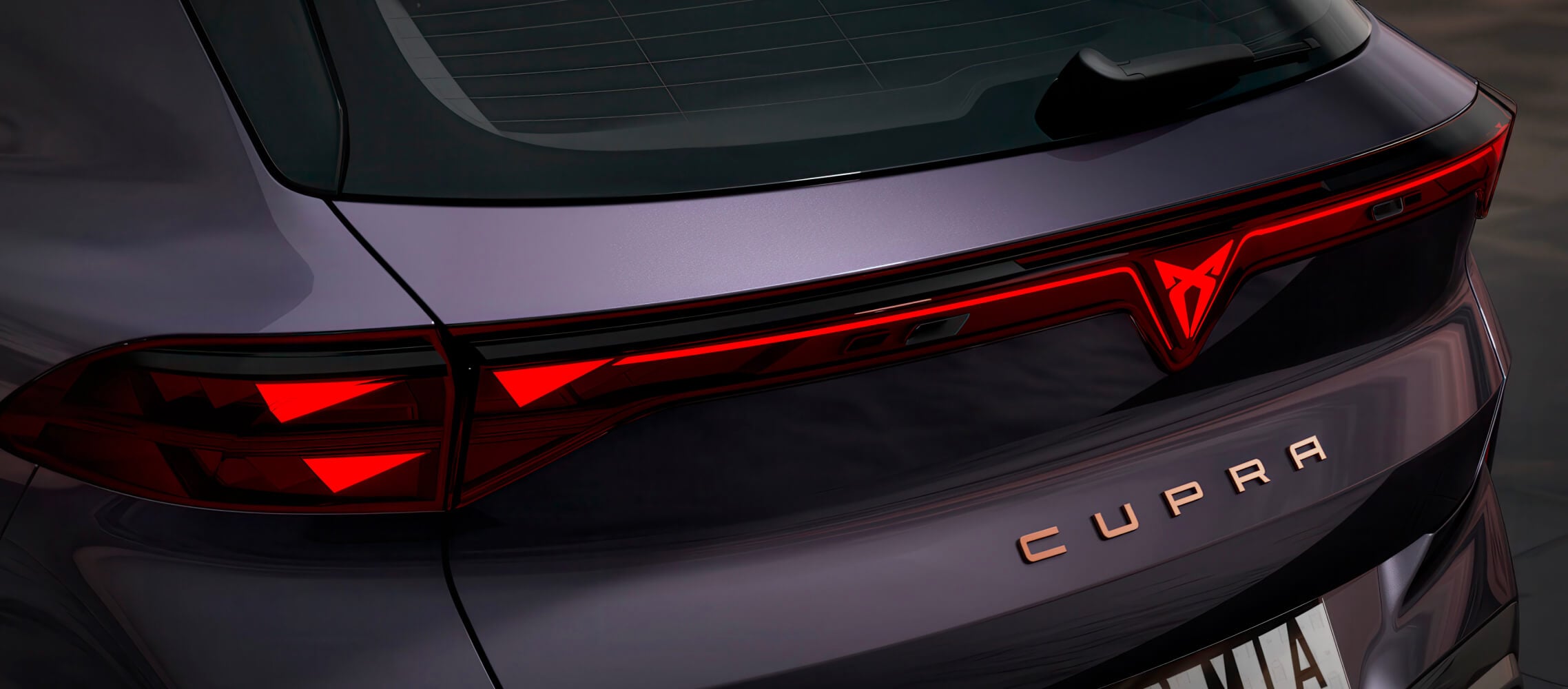 Close up of CUPRA Terramar VZ rear in the colour, dark void, PHEV rear lights with the illuminated CUPRA logo and copper accent lettering.